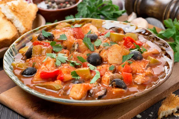 Fischragout mit Oliven in Tomatensauce auf einem Teller, Nahaufnahme — Stockfoto