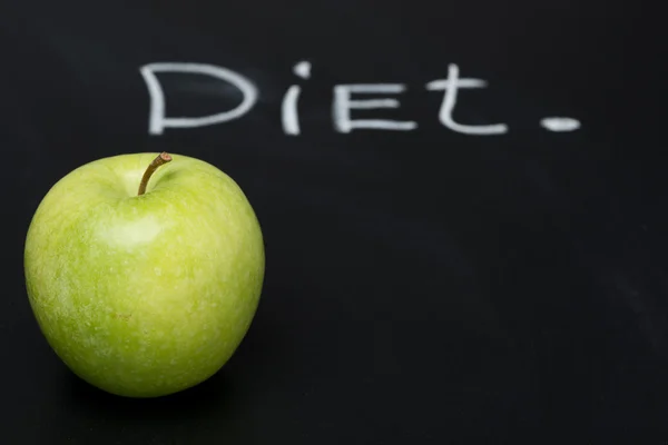 Green apple on a dark background and the word diet — Stock Photo, Image