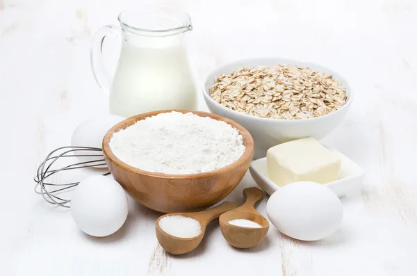 Молоко, хлопья и ингредиенты для выпечки на белом деревянном столе — стоковое фото
