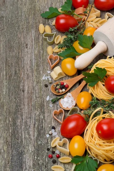 Makaron, przyprawy, zioła i pomidory na tle drewniane — Zdjęcie stockowe