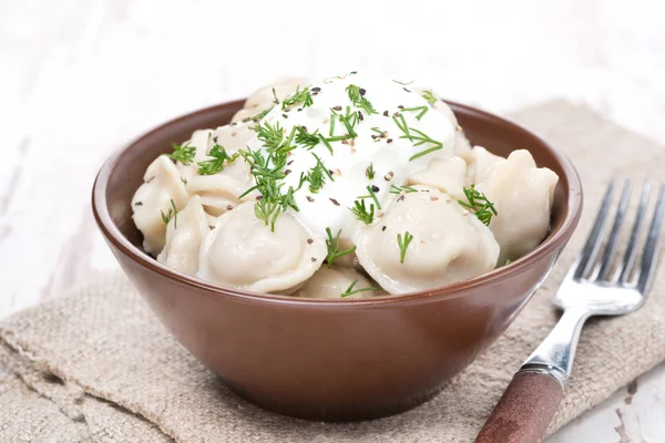 Traditional dumplings with sour cream in a bowl — Stock Photo, Image