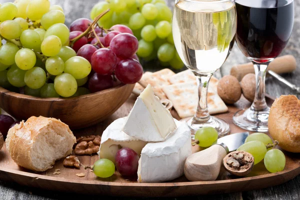 Camembert, vers stokbrood, druiven en wijn op een houten dienblad — Stockfoto