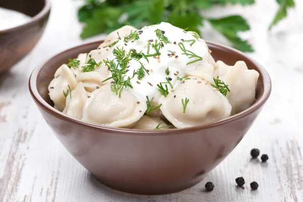 Traditional Russian dumplings with sour cream and dill, close-up — Stock Photo, Image