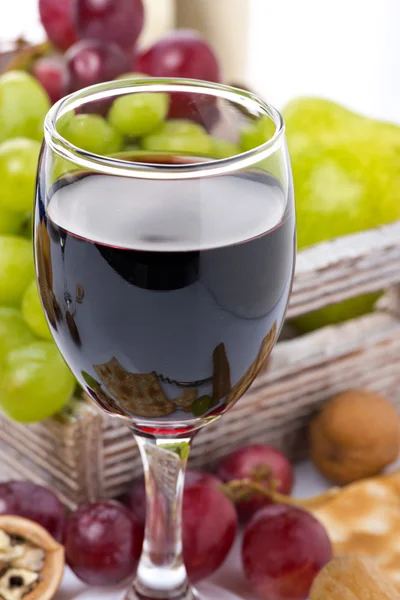 Glas Rotwein und Trauben im Hintergrund — Stockfoto