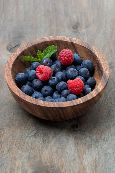 Wooden bowl with blueberries and raspberries — Stock Photo, Image