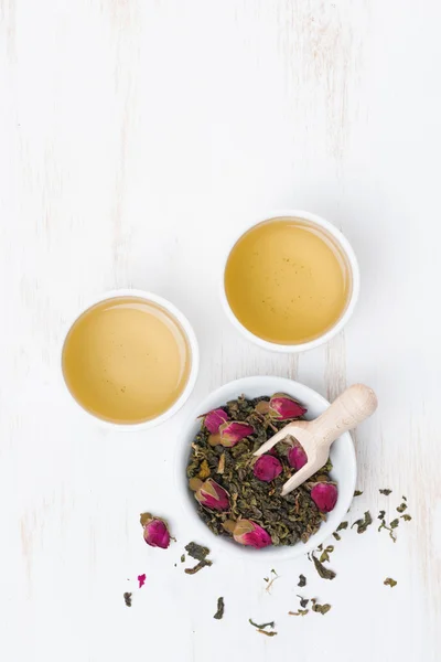 Green tea with rosebuds and cups on a white table, top view — Stock Photo, Image