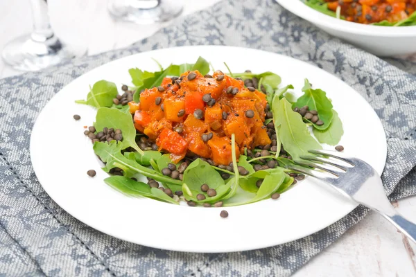 Sallad med rucola, svarta linser och grönsaksgryta på tallrik — Stockfoto