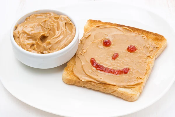 Toast with peanut butter and a painted smile — Stock Photo, Image