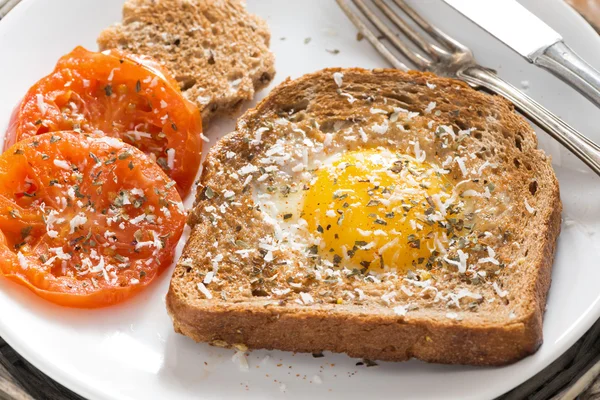 Fried egg and tomatoes in a toast for breakfast, close-up — Stock Photo, Image