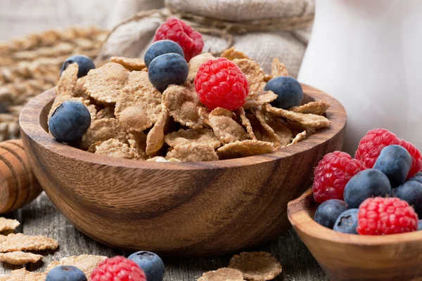 Wholegrain flakes with berries in a wooden bowl, close-up — Stock Photo, Image