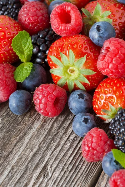 Sortierte frische Beeren auf Holzgrund, vertikal — Stockfoto