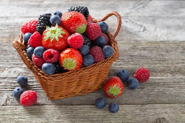 Basket of fresh seasonal berries on wooden table, top view — Stock Photo, Image