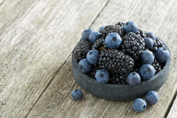 Cuenco de moras frescas y arándanos sobre fondo de madera —  Fotos de Stock