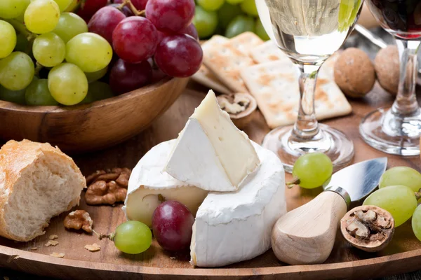 Camembert, baguete fresca, uvas e vinho em uma bandeja de madeira — Fotografia de Stock
