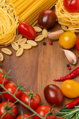 makarna, baharat ve ahşap tahta üzerinde domates
