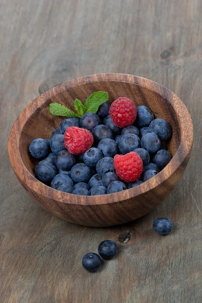 Wooden bowl with fresh blueberries and raspberries, vertical — Stock Photo, Image