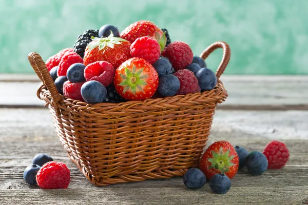 Basket with fresh juicy berries on a wooden table, horizontal — Stock Photo, Image