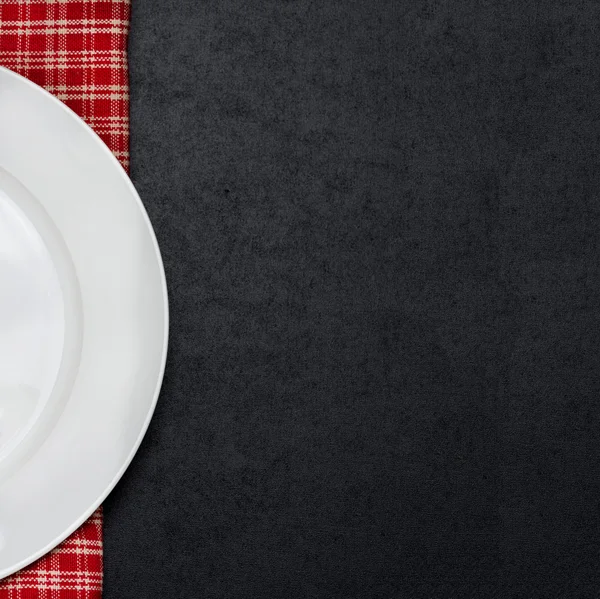 Parte del plato blanco vacío en una servilleta a cuadros — Foto de Stock