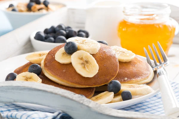 Panquecas com banana, mel e mirtilos frescos para o pequeno-almoço — Fotografia de Stock