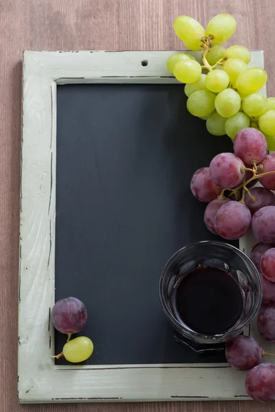 Blackboard voor het schrijven, glas rode wijn en druiven, bovenaanzicht — Stockfoto