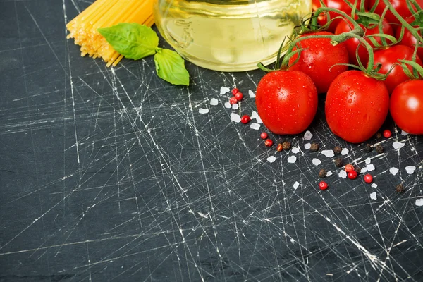 Dark background with cherry tomatoes, pasta, basil and olive oil — Stock Photo, Image