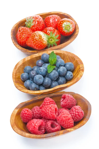 Verse frambozen, bosbessen en aardbeien in een houten kom — Stockfoto