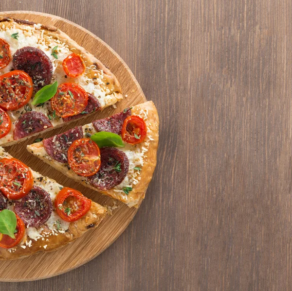 İtalyan pizza salam ve ahşap zemin üzerine domates ile — Stok fotoğraf