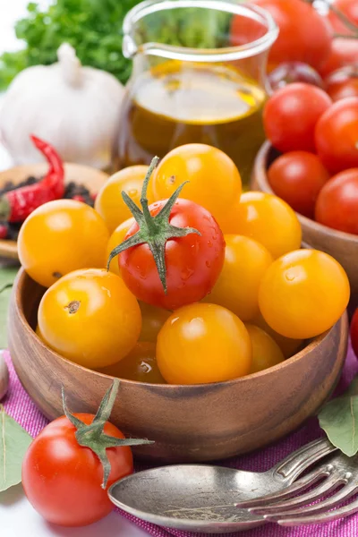 Yellow and red cherry tomatoes in wooden bowl, olive oil — Stock Photo, Image