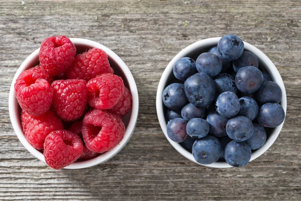 Raspberries and blueberries in bowls, top view — Stock Photo, Image