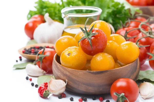 Yellow and red cherry tomatoes in wooden bowl, olive oil, herbs — Stock Photo, Image