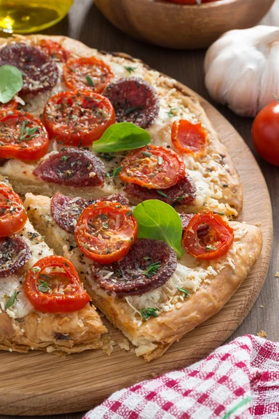 Leckere Pizza mit Salami und Tomaten auf einem Holzbrett — Stockfoto