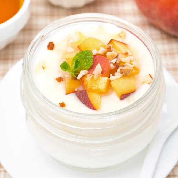 Vanilla yogurt with fresh peaches and nuts, top view — Stock Photo, Image