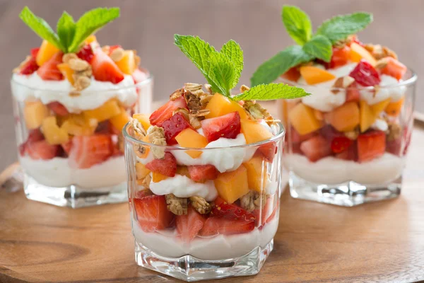 fruit dessert with whipped cream and granola in a glass