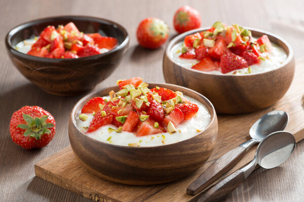 yogurt with fresh strawberries and pistachios in a wooden bowls
