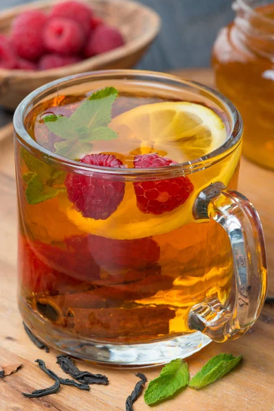 Black tea with lemon, mint, raspberry and cinnamon, close-up — Stock Photo, Image