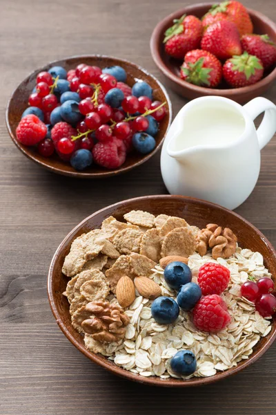 Oatmeal and muesli in a bowl, fresh berries and milk on wooden — Stock Photo, Image