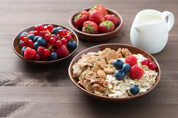 Harina de avena y muesli en un tazón, bayas frescas y leche —  Fotos de Stock