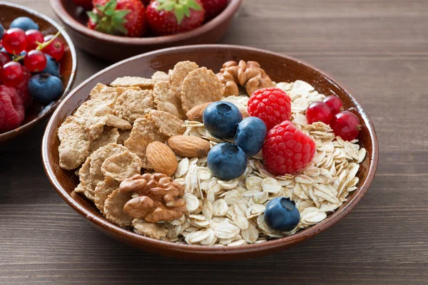 Harina de avena y muesli en un tazón, bayas frescas sobre fondo de madera — Foto de Stock