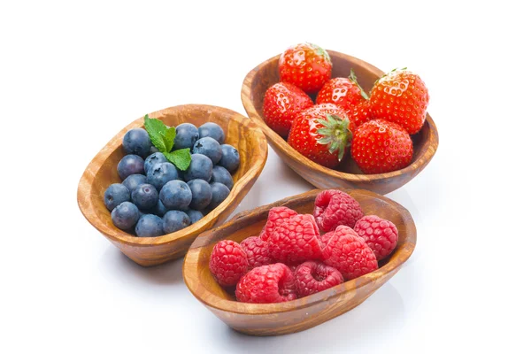 Raspberries, blueberries and strawberries in a wooden bowls — Stock Photo, Image