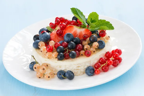 Mini cheesecake com bagas frescas em um fundo azul — Fotografia de Stock