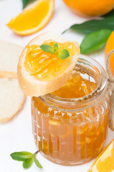 Orange jam in a glass jar and fresh baguette — Stock Photo, Image