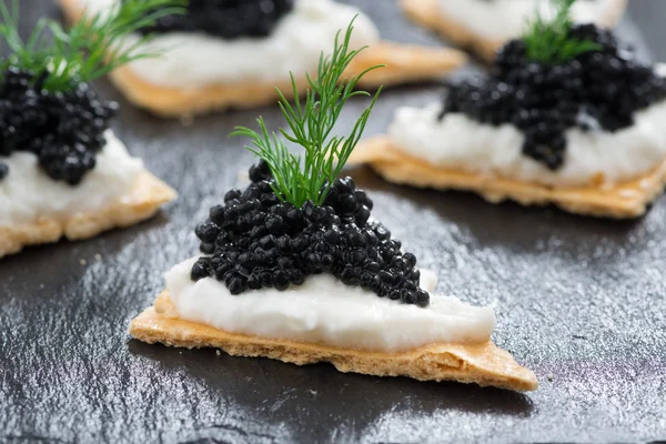 Galletas saladas con queso crema y caviar negro —  Fotos de Stock