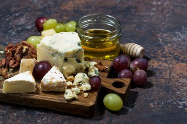 Cheeseboard, taze meyve ve bal koyu bir masada, yatay