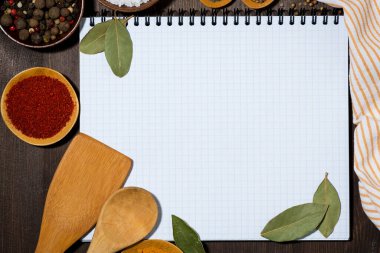 Yemek tarifleri, mutfak kaşıkları ve baharatlar için açık defter tahta arka plan kavramı, yakın çekim üst görünüm