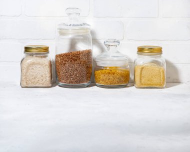 Cam kavanozlardaki mısır gevrekleri beyaz bir masada, yatay olarak.