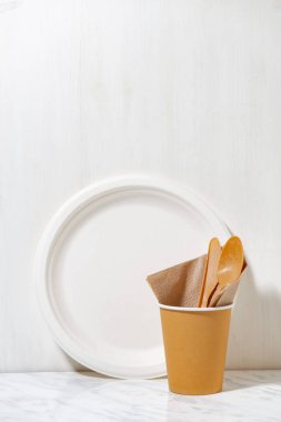 Beyaz arka planda geri dönüştürülmüş malzemelerden yapılan çevre dostu tek kullanımlık sofra takımı, yakın plan