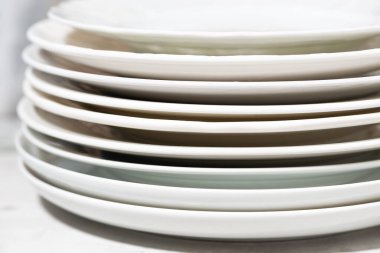 Beyaz bir masanın üzerindeki temiz tabak yığını, yakın plan.