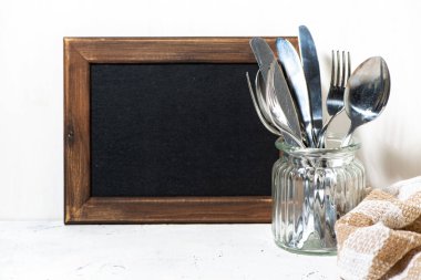 Siyah tahta yemek tarifleri ve çatal bıçak takımlarını bardağa koymak için, yakın plan.