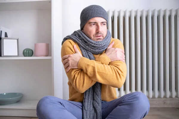 Bir adam evde üşümüş ve ısıtma sorunu yaşıyor.