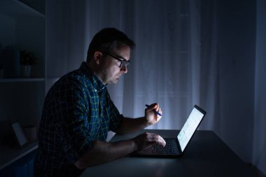 Bir adam gece geç saatlere kadar bilgisayar başında çalışıyor.